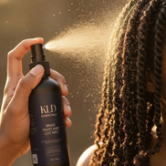 Person using a KLD hair product on their braided hair with a blurred background