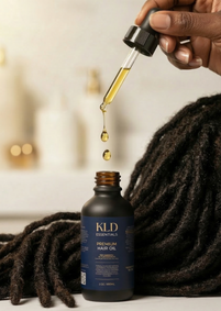 KLD Essentials hair oil bottle with dropper over textured hair